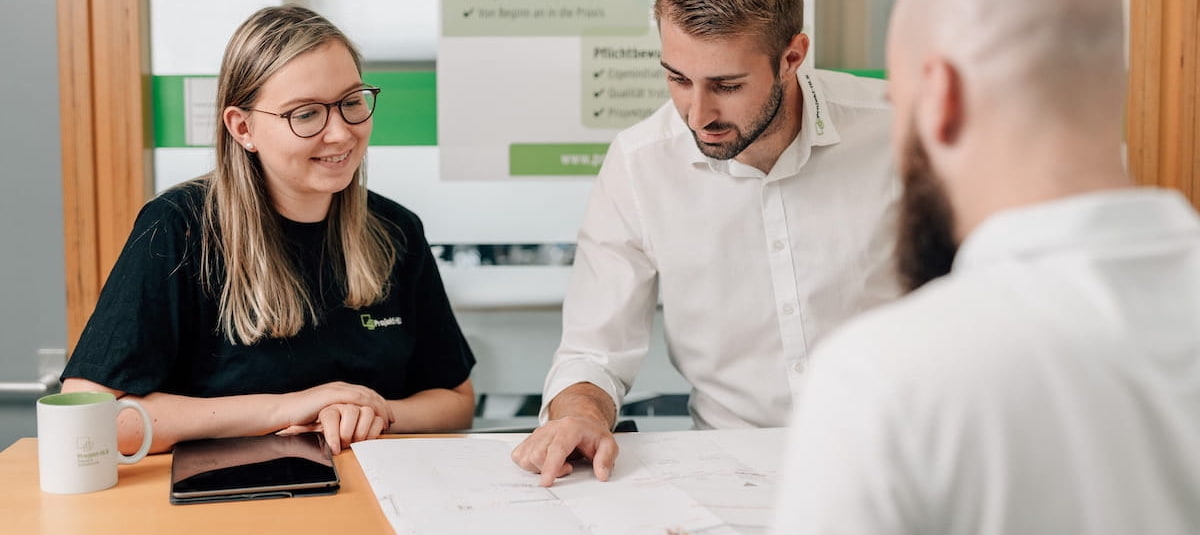 Drei Projektplaner beim Planungsbüro Projekt HLS besprechen einen Plan