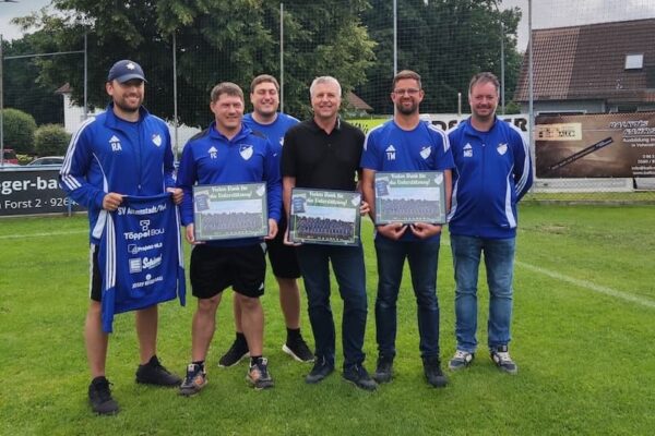 Sponsoring von Projekt-HLS Weiden: Mannschaftsvertreter des SV Altenstadt bei Vohenstrauß in blauen Trikots präsentieren mit Prokurist Martin Voit neue Trainingskleidung auf dem Sportplatz.