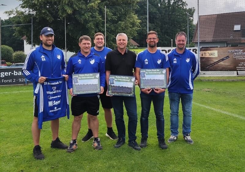 Sponsoring von Projekt-HLS Weiden: Mannschaftsvertreter des SV Altenstadt bei Vohenstrauß in blauen Trikots präsentieren mit Prokurist Martin Voit neue Trainingskleidung auf dem Sportplatz.